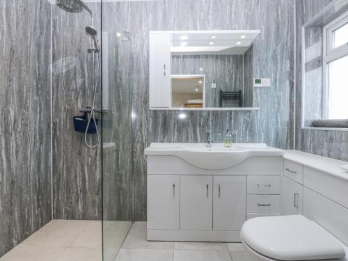 a bathroom with a white sink and a shower at Benlli in Pwllheli