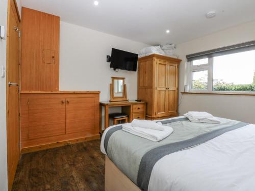 a bedroom with a bed and a dresser with towels at Benlli in Pwllheli