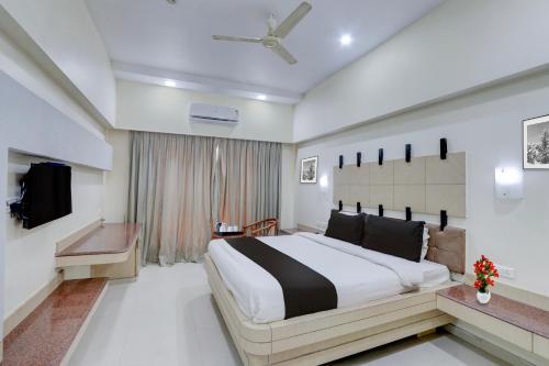 a bedroom with a large bed and a television at Townhouse Kakinada Nagamalli Thota Junction in Kākināda