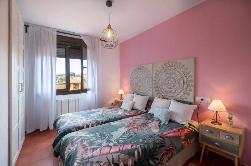 een slaapkamer met 2 bedden en een roze muur bij Villa vacacional Taty in Llanes