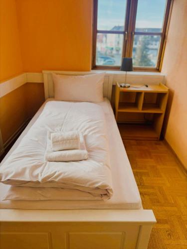 a bed with a white blanket and a window at Markt Eins Salonwohnung in Schöppenstedt