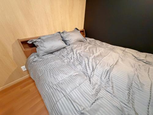 Una cama deshecha en un dormitorio con una pared de madera. en A Lucky Hostel, en Hakuba