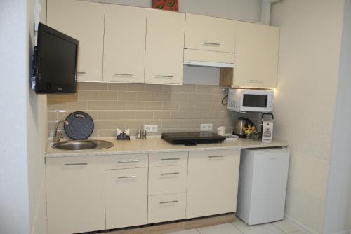 eine Küche mit weißen Schränken, einer Spüle und einem Kühlschrank in der Unterkunft Смарт-квартира in Bucha