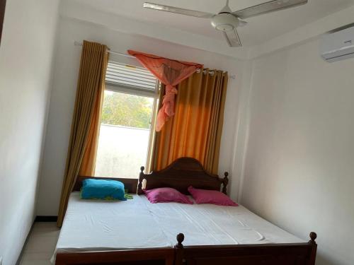 um quarto com uma cama com duas almofadas e uma janela em Kaushi Home em Kottawa