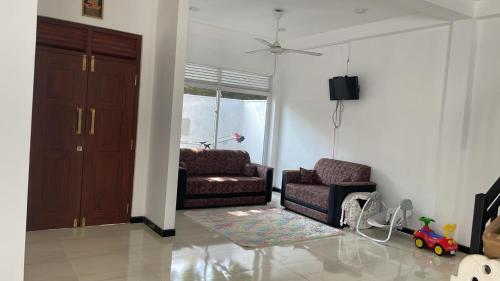 uma sala de estar com um sofá e uma cadeira em Kaushi Home em Kottawa