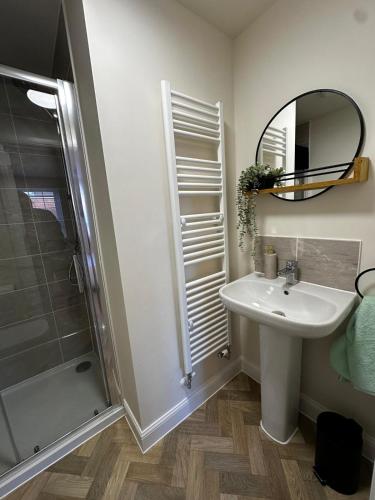 a bathroom with a sink and a shower and a mirror at Olive Tree House in Edwinstowe