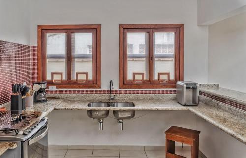 a kitchen with a sink and two windows at 400 m te Separam das Areias da Praia de Boraceia, casa com piscina aquecida para ate 12 pessoas in São Sebastião