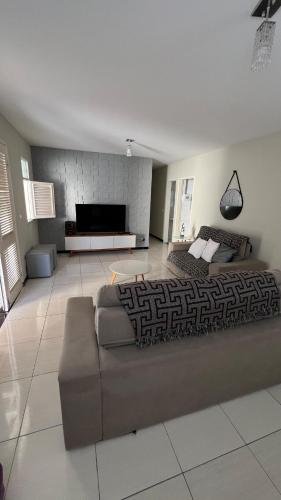 Piranhas casa de temporada في ببرانا: غرفة معيشة مع أريكة وتلفزيون بشاشة مسطحة