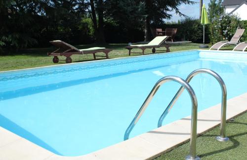 a blue swimming pool with two chairs and two benches at La Maison Rouge Ladoix - Proche Beaune in Ladoix Serrigny