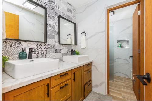 a bathroom with two sinks and a mirror and a shower at El Neptuno Residencial, Sosua in Sosúa