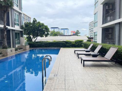 een zwembad met ligstoelen naast een gebouw bij studio123 at Changwattana in Ban Bang Phang