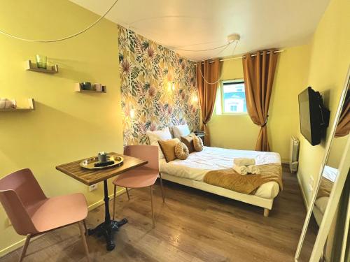 une petite pièce avec un lit, une table et des chaises dans l'établissement la bonbonnière Jaune, à Caen