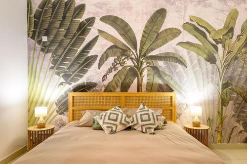 a bedroom with a bed with a mural of palm trees at Lamarel Beach House 2 in Flic-en-Flac