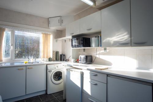 a white kitchen with a washing machine and a window at Ideal for Contractors & Families in Loughborough