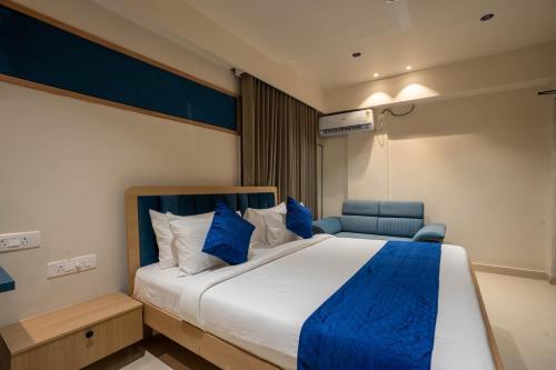 a bedroom with a large bed and a blue chair at Sasya Elegance - A Boutique Hotel in Lingampalli