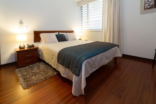 una camera da letto con un letto grande, un comodino e una finestra di Suites Metropoli Edificio Torino a Quito