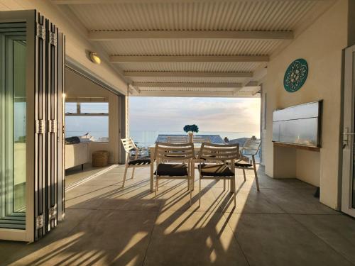 Seegeluk, magnificent beach house in De Kelders في دو كيلدرز: فناء مع طاولة وكراسي على شرفة