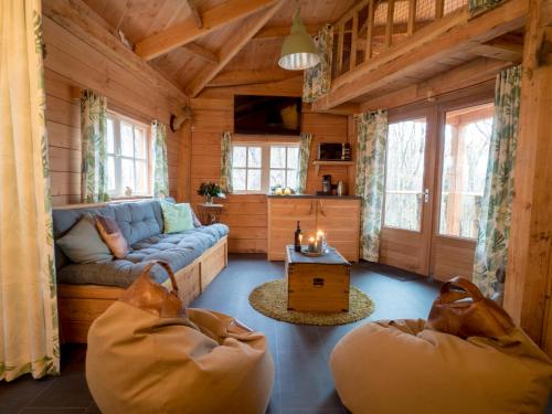 a living room with a couch and a table at Boomhut XXL in Hoogersmilde