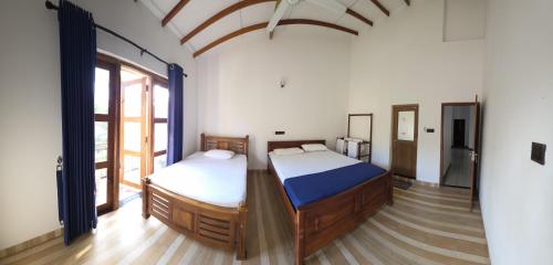 Aruna homestay في بولوناروا: غرفة نوم بها سريرين ونافذة كبيرة