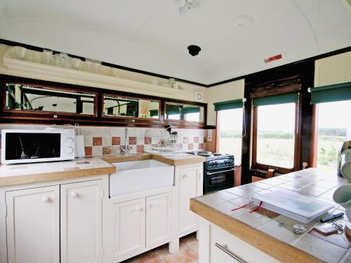 a kitchen with white cabinets and a white microwave at Railway Carriage Two - E5601 in Wetheringsett