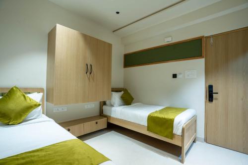 Sasya Elegance - A Boutique Hotel في Lingampalli: غرفة نوم صغيرة مع سريرين وخزانة