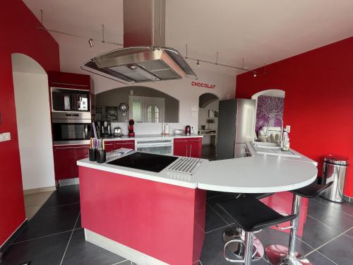 une cuisine avec des armoires rouges et un comptoir blanc dans l'établissement Villa Oyala avec piscine, spacieuse et de qualite, à Saint-Pierre-dʼOléron