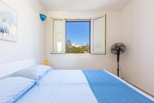 een slaapkamer met een bed, een ventilator en 2 ramen bij Casa Agnese by BarbarHouse in Leuca