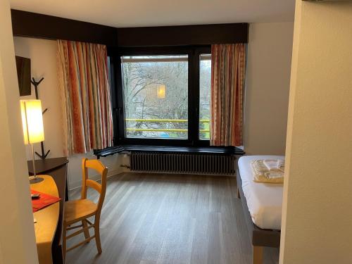 a room with a bed and a desk and a window at Medical Wellness RehaKlinik und Aqualon Therme in Bad Säckingen