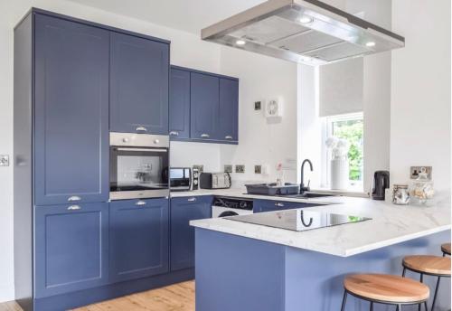 a kitchen with blue cabinets and a counter top at 5 Bed cottage with Hot tub in Bannockburn