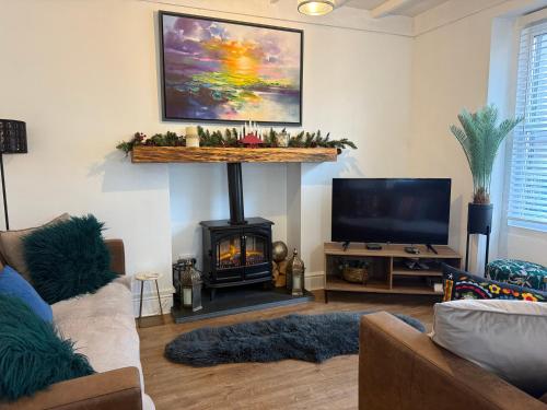 a living room with a fireplace and a television at Family Cottage in Llandudno with Parking in Llandudno