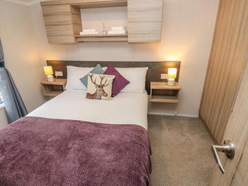 a bedroom with a bed with pillows and two lamps at Woodland View in Skipton