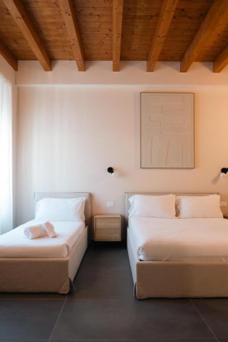 two beds in a room with wooden ceilings at Tower Triple Suite - 3 min walk to Bernina Express in Tirano