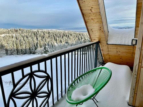 a green chair sitting on a balcony with a view at Domek Tatry - Stacja Wierchowa 972 m in Brzegi