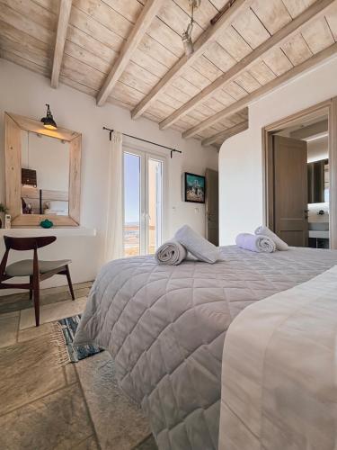 a bedroom with two beds and a table and a window at Elysian Villas Ios in Ios Chora