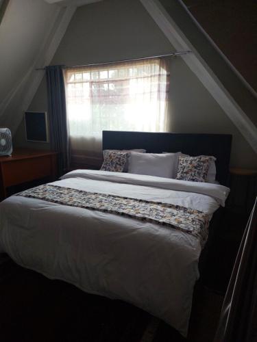 Un dormitorio con una cama grande con ventana. en Yukis & Kukis Place 5 Bedrooms, en Embu