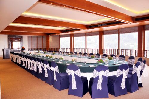 ein großer Bankettsaal mit einem langen Tisch und blauen Stühlen in der Unterkunft Radisson Hotel Shimla in Shimla