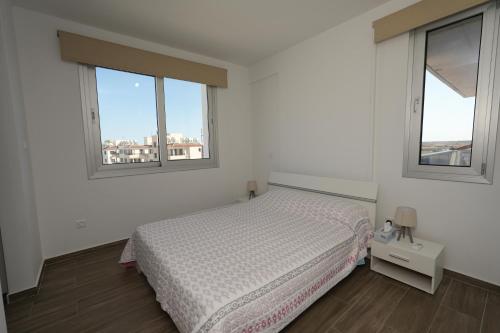 Larnaca Salt Lake Gem, Airy 2 BDRM Apartment في لارنكا: غرفة نوم بيضاء مع سرير ونافذتين
