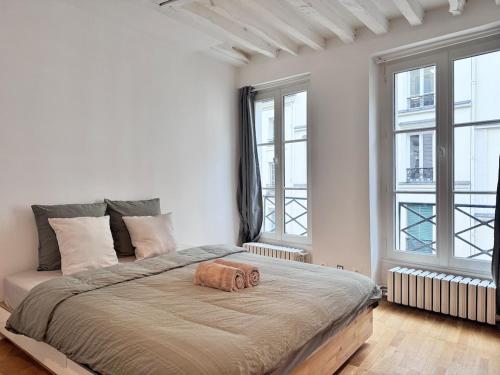 une chambre avec un grand lit avec deux fenêtres dans l'établissement Sentier, à Paris