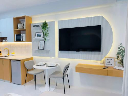 Una sala de estar con una mesa y un televisor en una pared. en Simple White Scape at Mesavirre Bacolod, en Bacolod