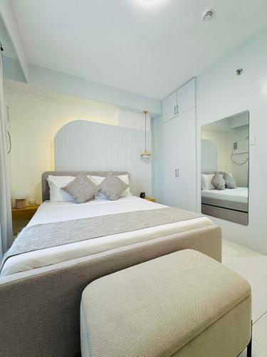 a bedroom with a large bed and a mirror at Simple White Scape at Mesavirre Bacolod in Bacolod