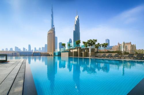 a swimming pool with a city skyline in the background at BRAND-NEW 1BR in DOWNTOWN I Direct DUBAI MALL Access I Balcony & Stunning Pool in Dubai