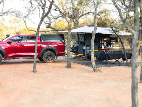 Un camión rojo estacionado frente a una tienda de campaña. en The Beehive Cabin, en Rhenosterfontein