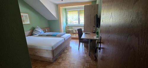 a bedroom with a bed and a desk and a window at Hotel - Pension Wendland in Wintrich