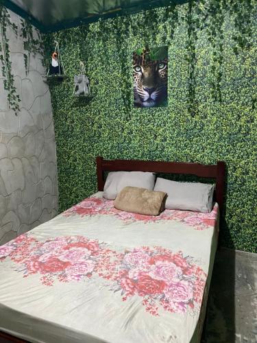 a bedroom with a green wall with a bed with flowers at Camping estrela Ubatuba in Ubatuba