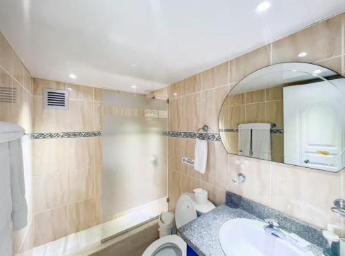 a bathroom with a sink and a toilet and a mirror at Garden Condo in Sosúa