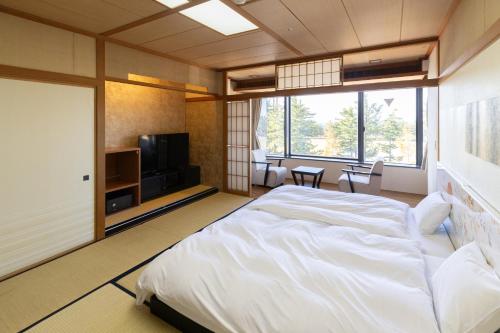 a bedroom with a large bed and a television at 9stayリゾートテクノポート福井 in Sakai