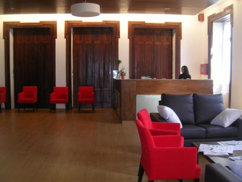 a waiting room with a couch and red chairs at Balneario Acuña in Caldas de Reis
