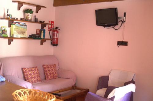 Una sala de estar con un sofá y un televisor en la pared. en Casa Angelita, en Intriago