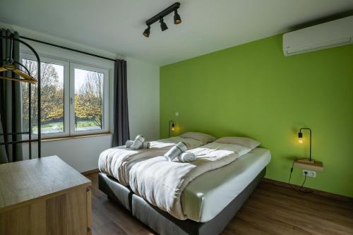 a bedroom with a large bed with green walls at Le Havre de la Forêt in Dochamps