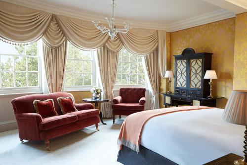 um quarto com uma cama, 2 cadeiras e janelas em The Goring em Londres